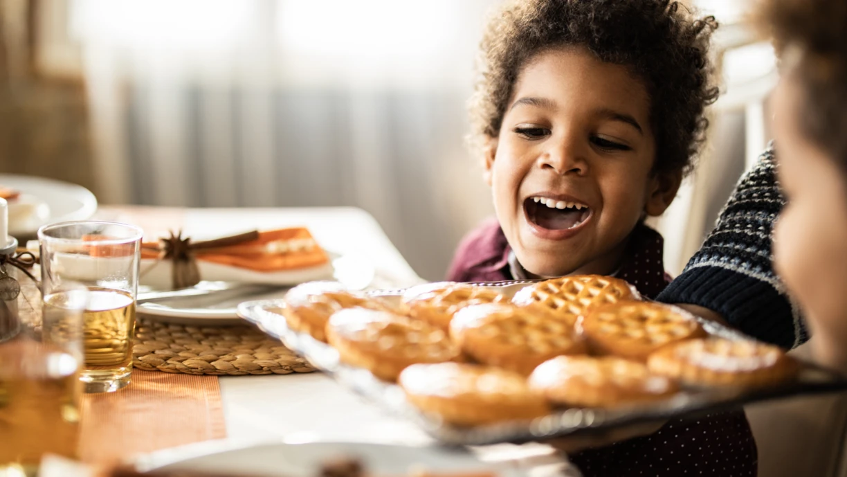 Kid sitting at a table looking at biscuits and cookies 