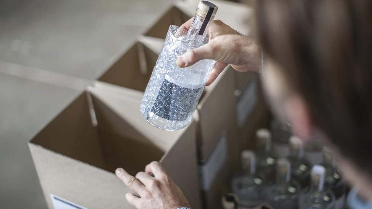 Man putting bottle of liquor into cardboard box