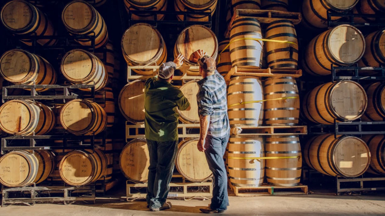 two wine makers standing in front of wine barrels