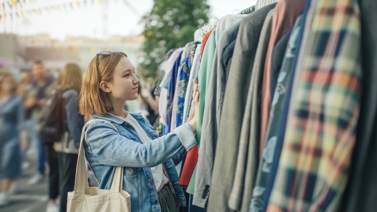 Young girl choosing clothes in a second hand market in summer