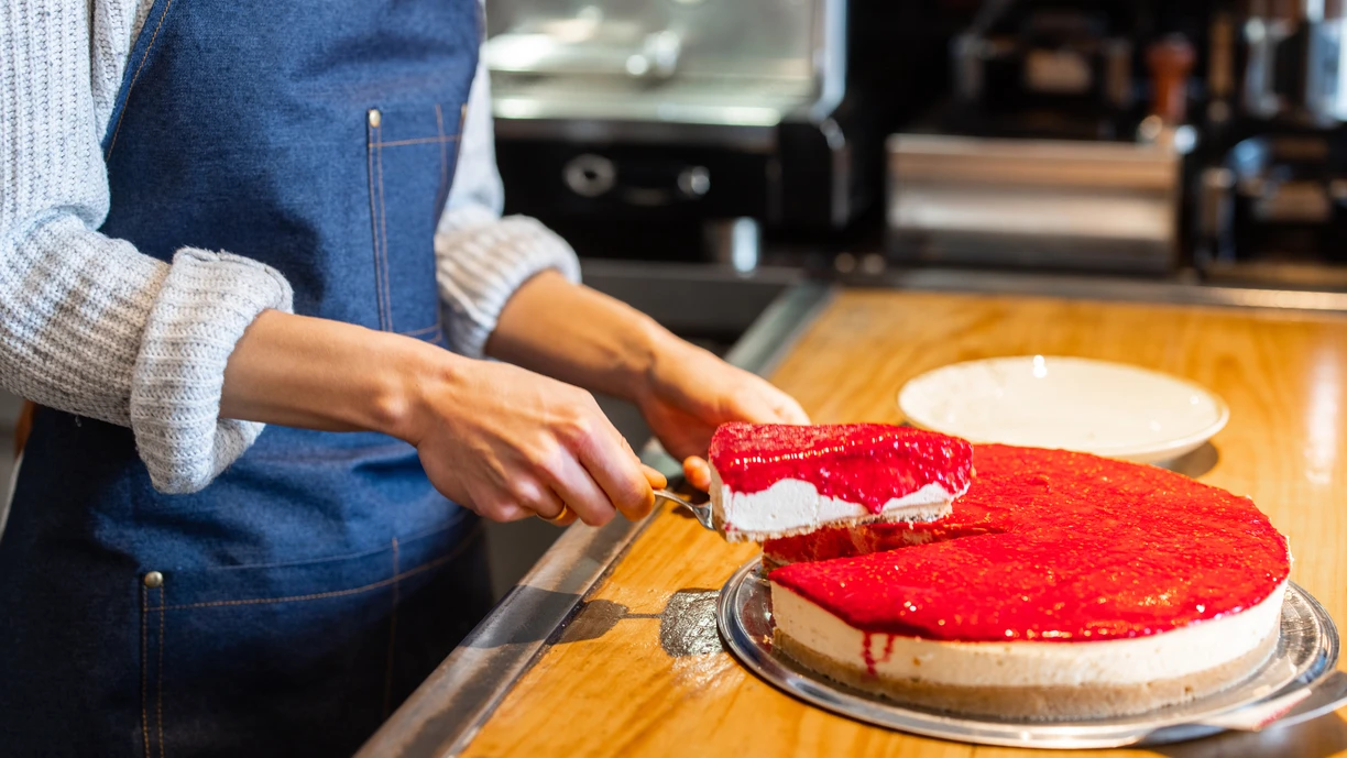 Close-up of a waitress serving a portion of rasberry cheesecake