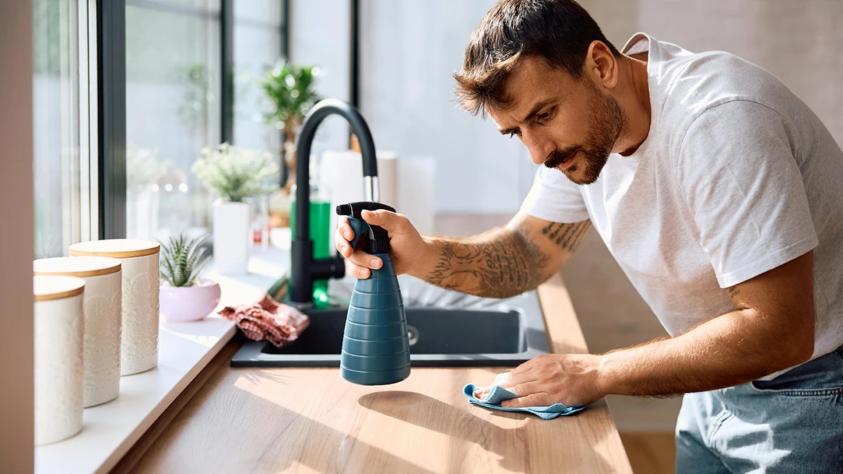 young man wiping kitchen counter