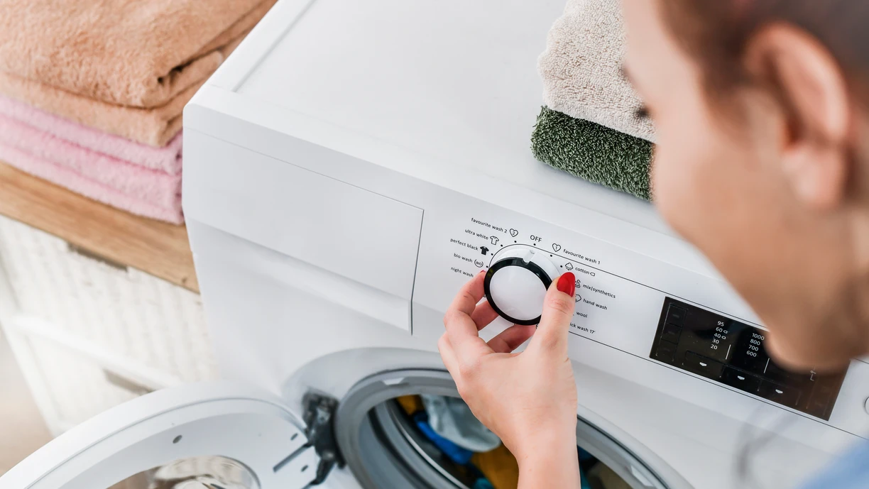 woman choosing laundry program on a washing machine