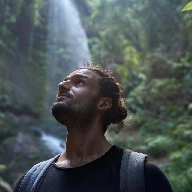 Guy with manbun in nature looking up