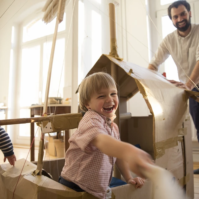 father and son playing with cardboard