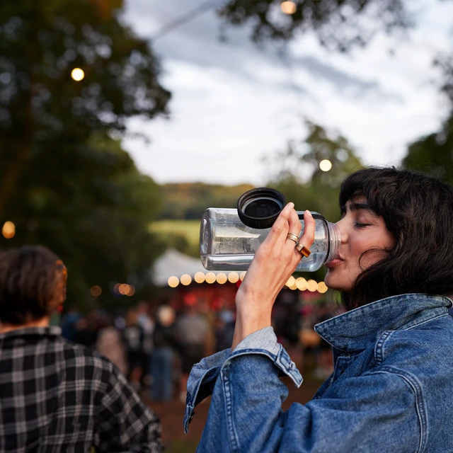 Woman with a denim jacket drinking from water bottle