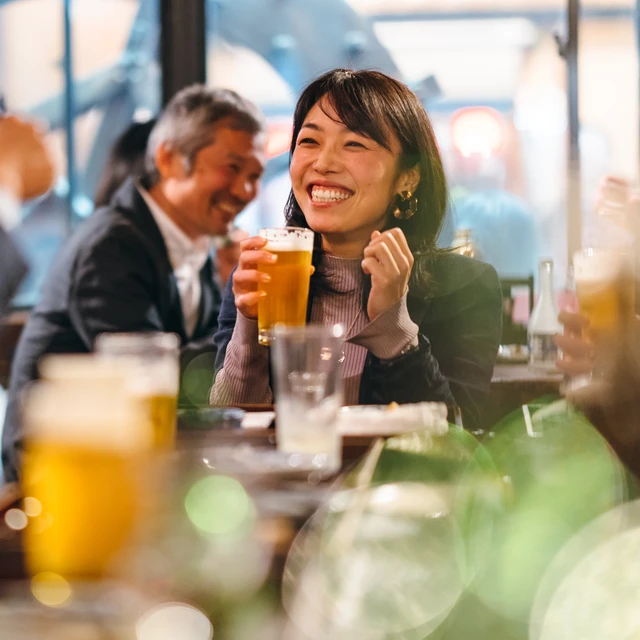 Asian girl smiling whilst drinking beer