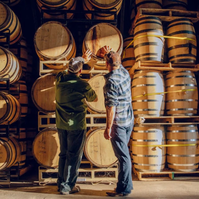 two wine makers standing in front of wine barrels