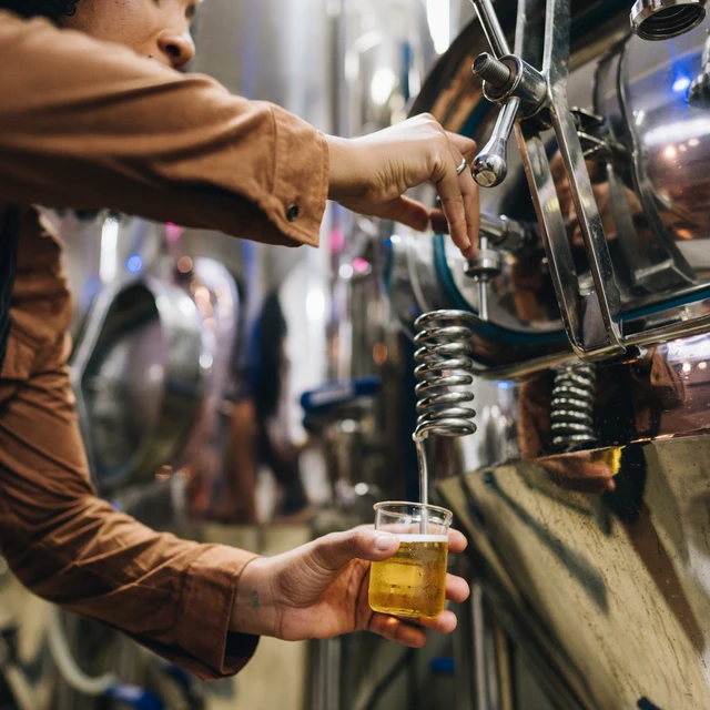 A brewer taking a beer sample from a tank