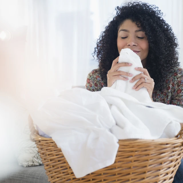 Mixed race woman smelling clean towels in laundry
