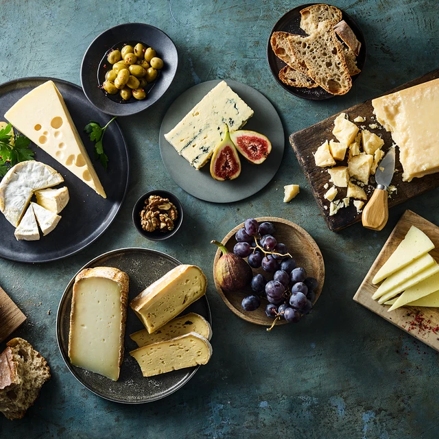 Assorted cheese platter with fruits, nuts, olives, and bread—arranged to improve cheese flavo