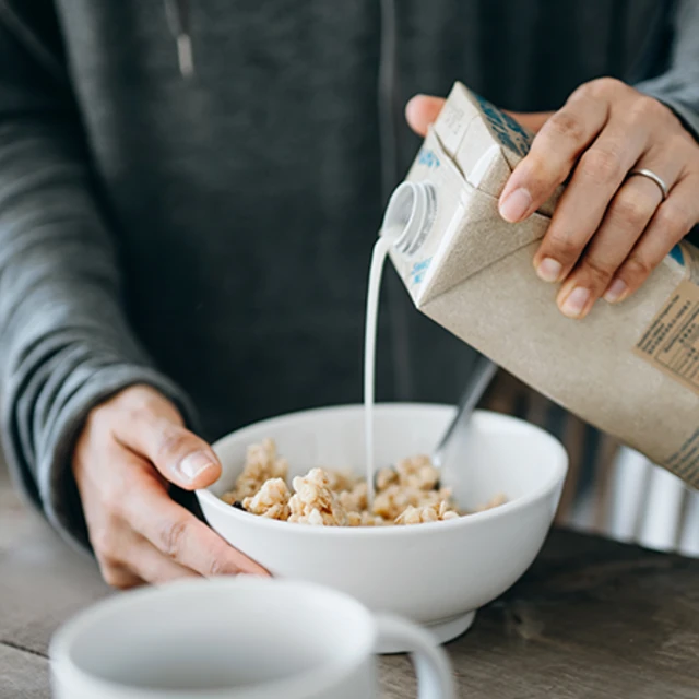 woman pouring milk over cereals on the kitchen counter