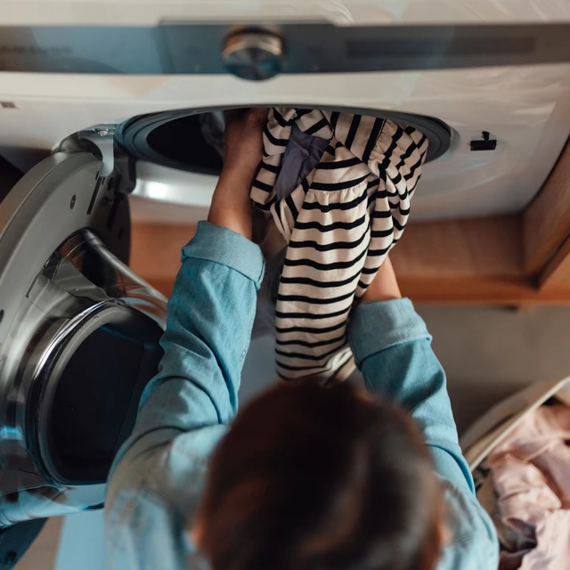 person putting clothes in washing machine