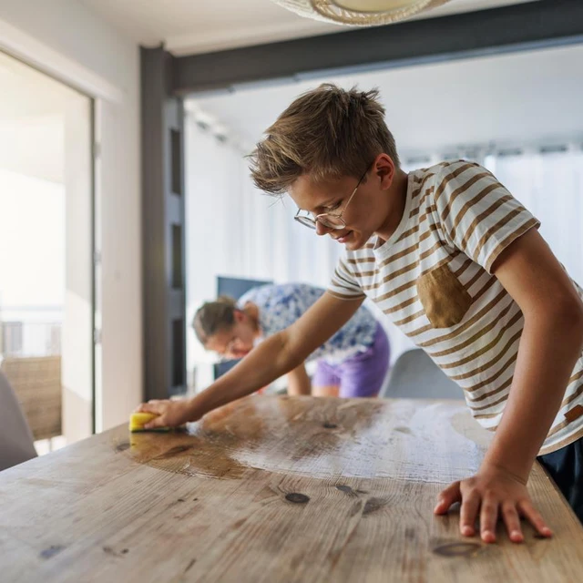 The boy is wiping the table