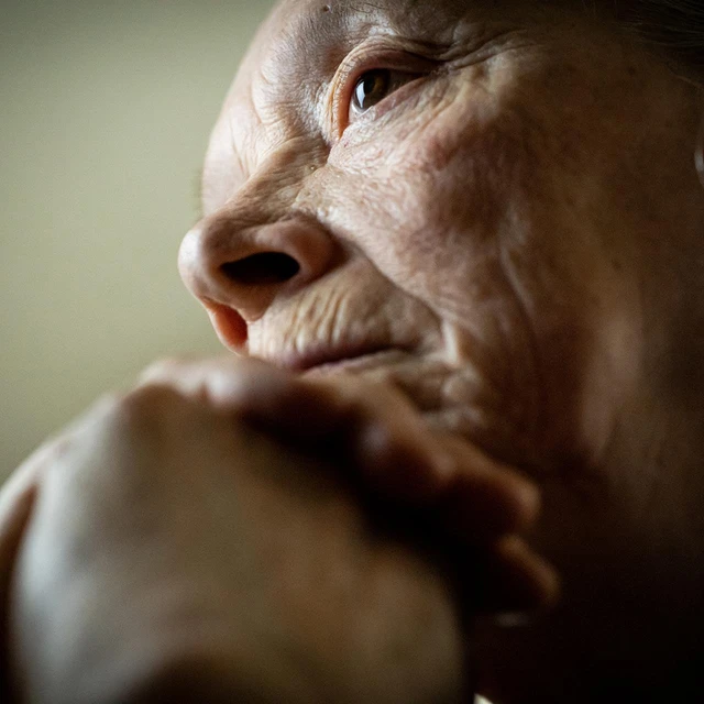 Close-up of an elderly woman resting her chin on her hand
