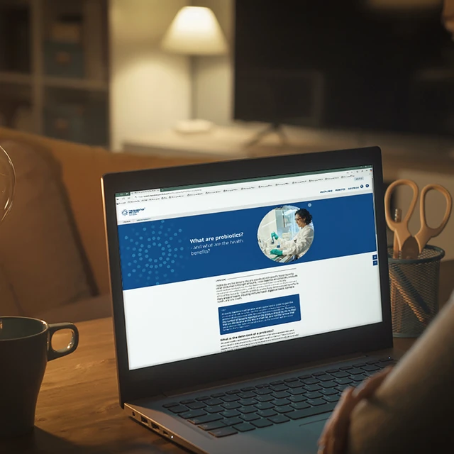 A young woman visiting The Probiotics Institute by Chr. Hansen™ on her laptop in her living room at night. 