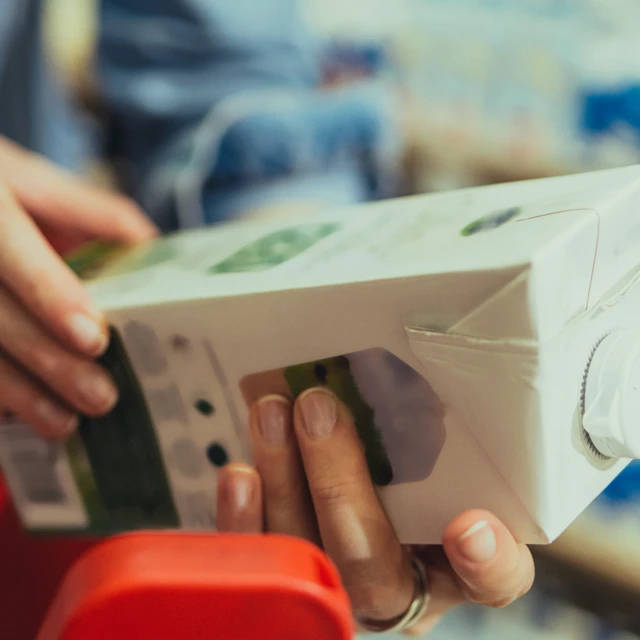 Hands Holding a Carton of Vegetable Milk in the Supermarke