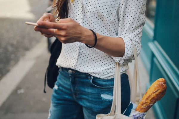 Woman holding a tote bag with a baguette inside