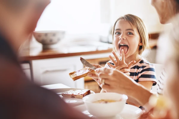Little girl enjoying tasty bread with family