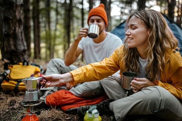 Girl and boy drinking coffee in the forest