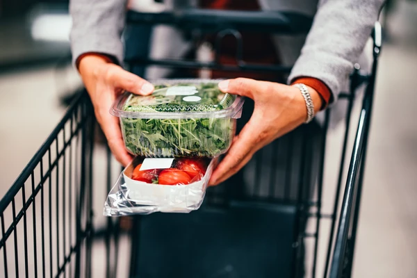 Man Placing plastic box of Vegetables in the Shopping Cart