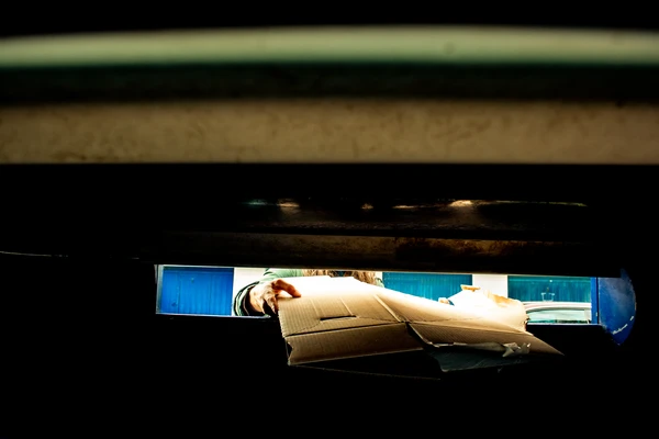 Woman putting cardboard into recycling bin