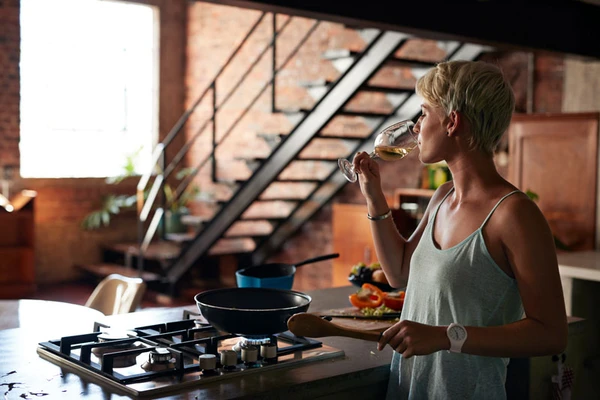 Woman drinking wine while making food