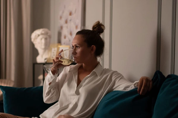 Woman sitting on sofa drinking white wine