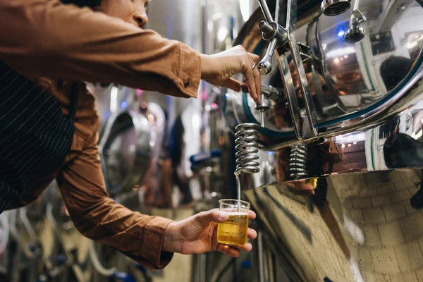 A brewer taking a beer sample from a tank 