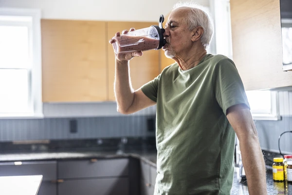 Senior man drinking a fruit smoothie at home