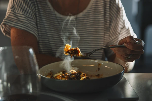 Woman eating fusilli pasta with bolognese sauce