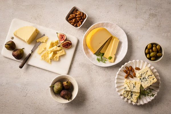 Plate with blue cheese slices, herbs, and olives—styled to highlight pairings that improve cheese flavor. 