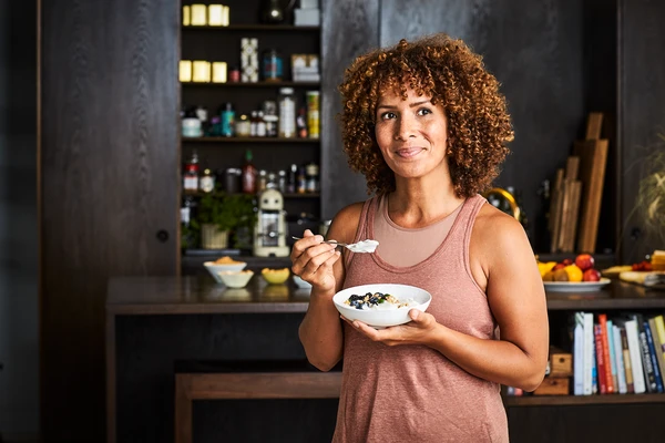 Woman eating a bowl of spoonable yogurt in her kitchen 
