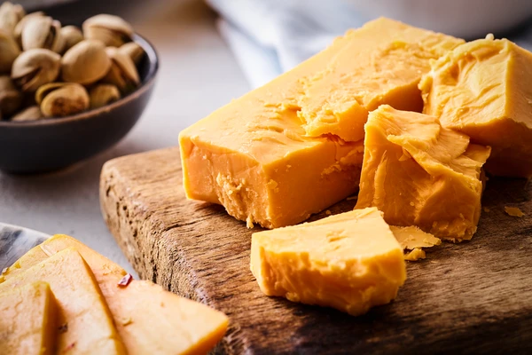 Close-up of a block crumbly, mature cheddar cheese on a wooden board 