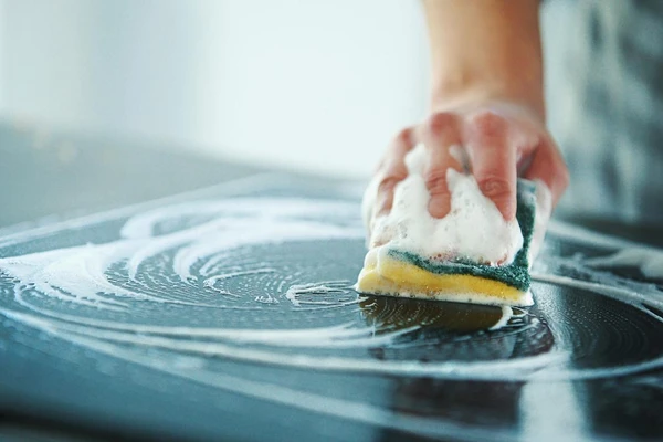 cleaning stove top with sponge