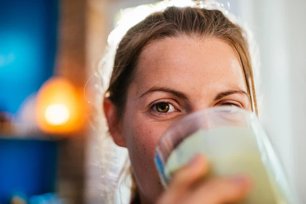 Close up on the face of a woman as she drinks from a glass of fermented milk 