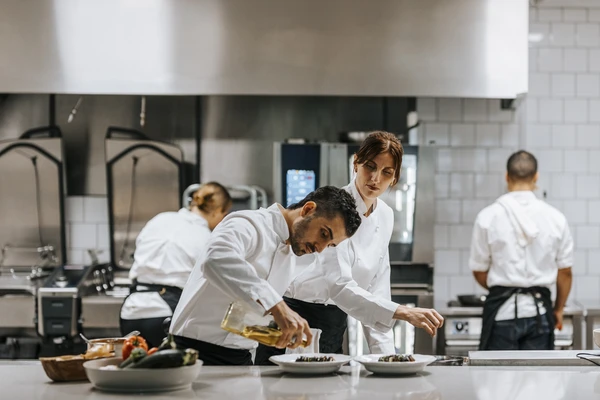 Male chef pouring oil on dish