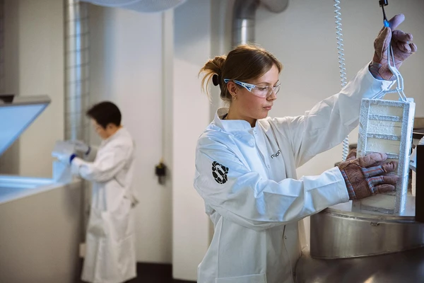 Female scientist in a lab coat carefully operating specialized laboratory equipment