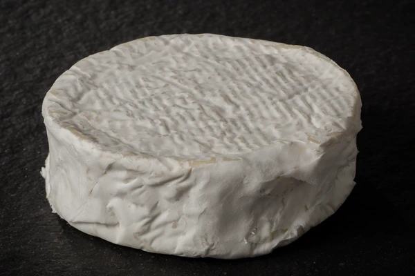 Close-up of a Camembert cheese wheel with a white, wrinkled rind—aged to improve cheese flavor and enhance buttery flavor. 