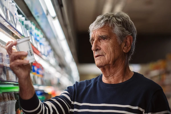 man looking at yogurt in supermarket