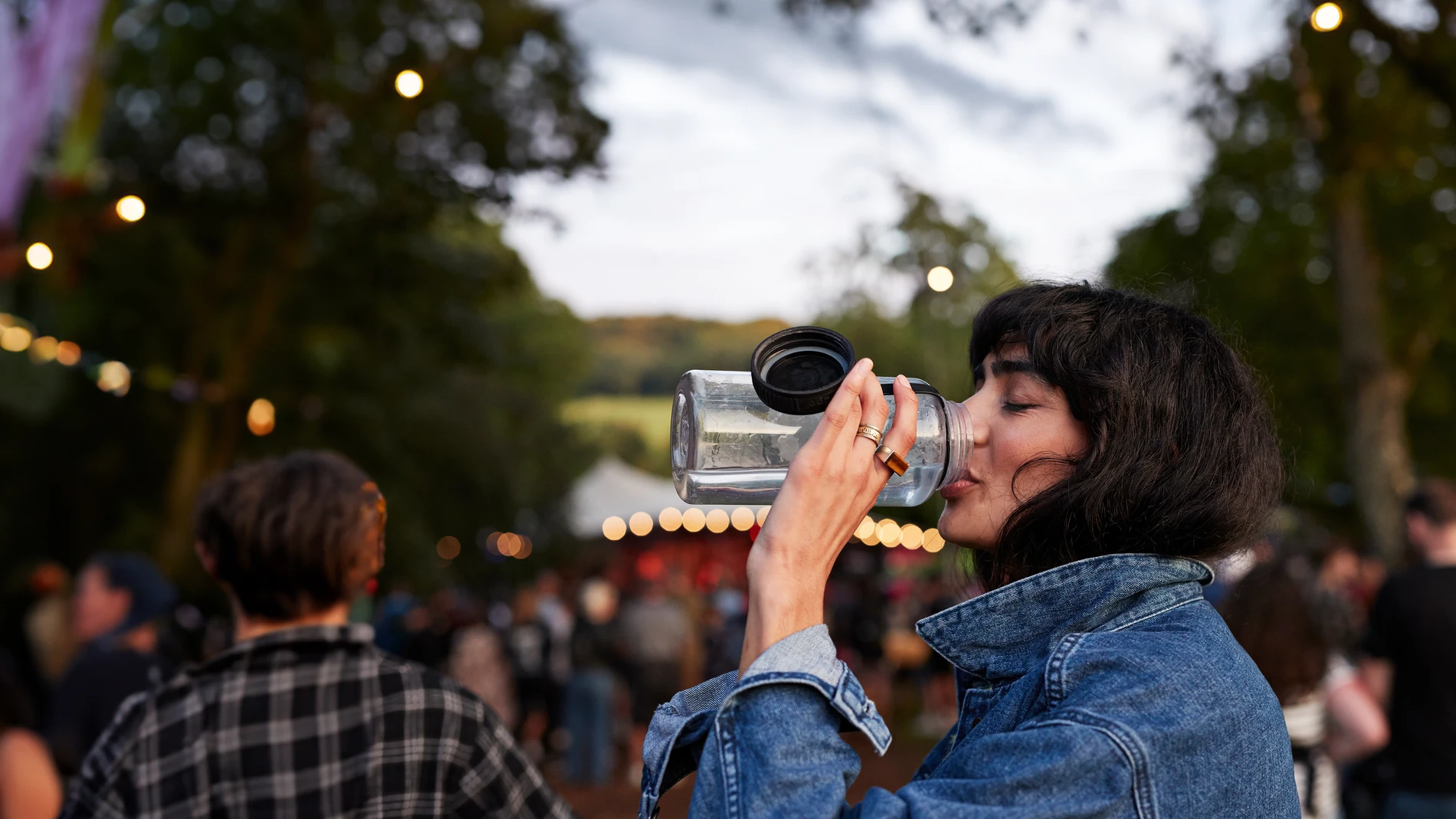 Woman with a denim jacket drinking from water bottle