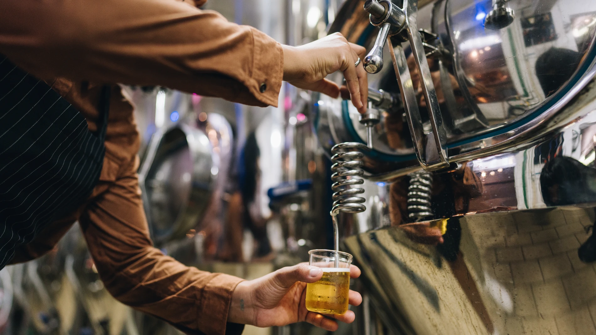 A brewer taking a beer sample from a tank