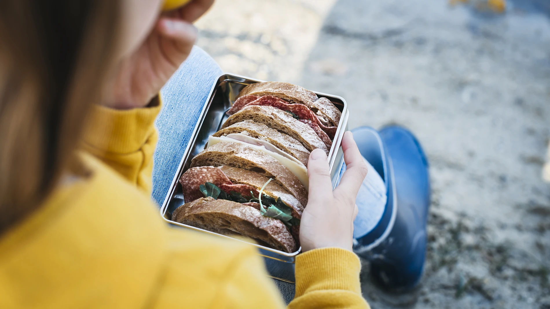 Girl in yellow clothing eating her lunch