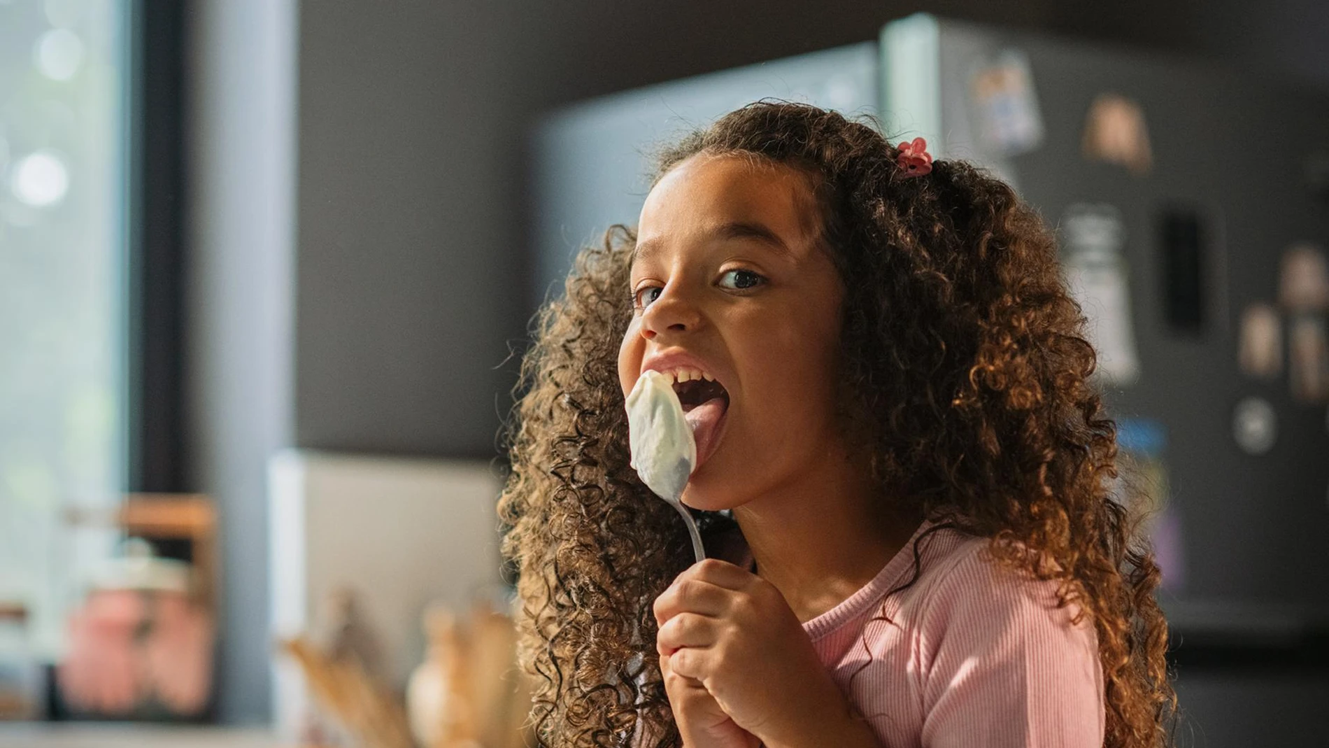 Girl licking spoon of yogurt