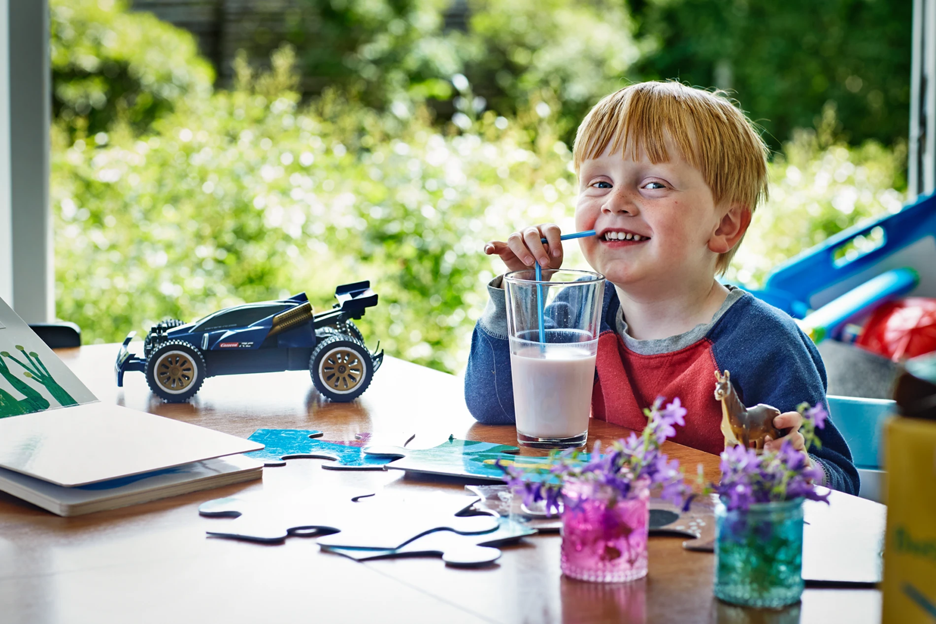 Child with red hair drinking a glass of milk at a table