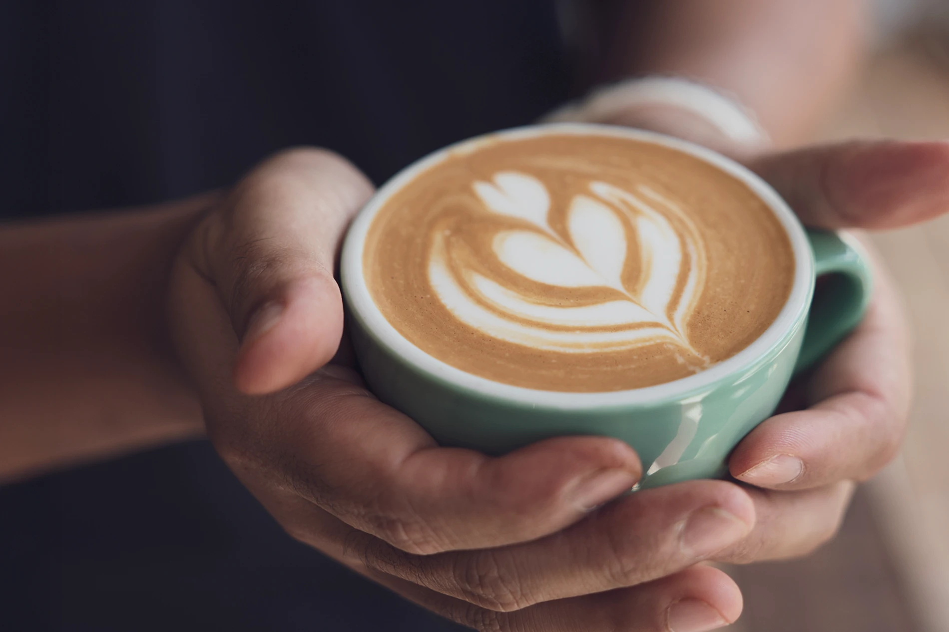 Hands holding cup of hot coffee latte cappuccino