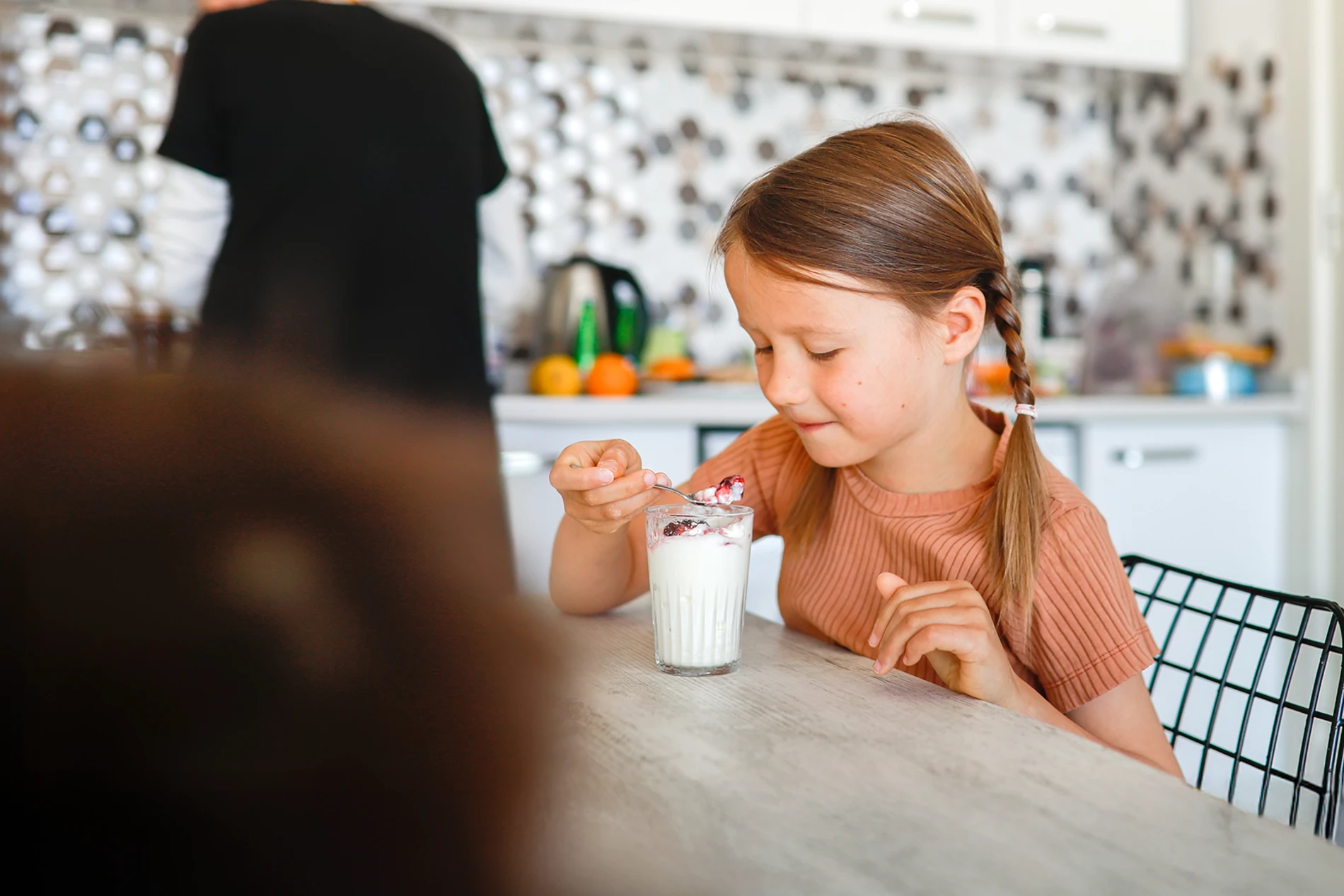 Young female hand eating peach yogurt with spoon.png