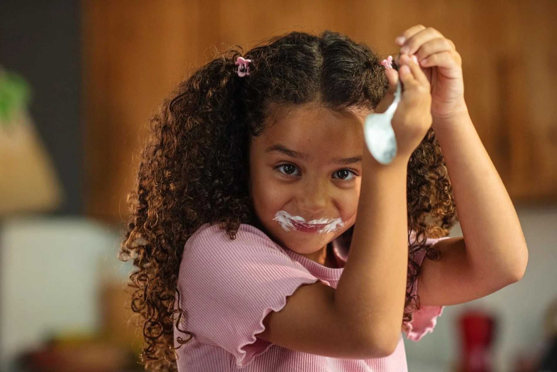 girl licking spoon of yoghurt